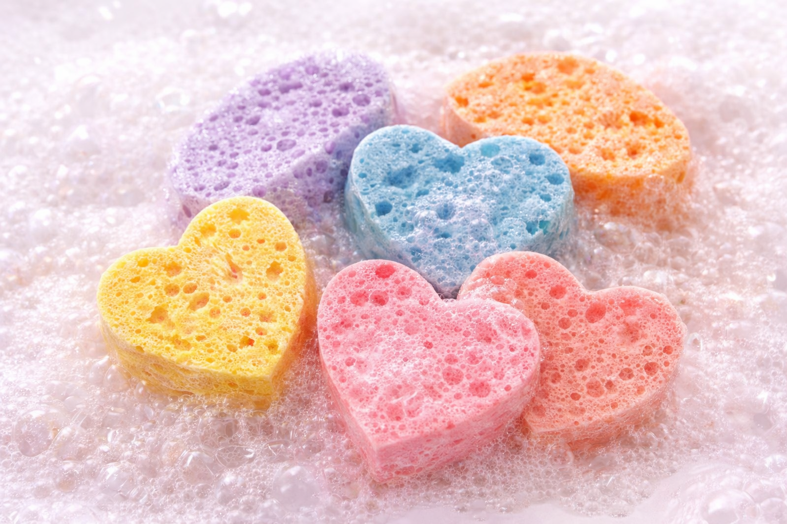 Soap-infused sponges by Always Bubbles in heart shapes and soft colors, creating rich bubbly lather for gentle exfoliation and cleansing.