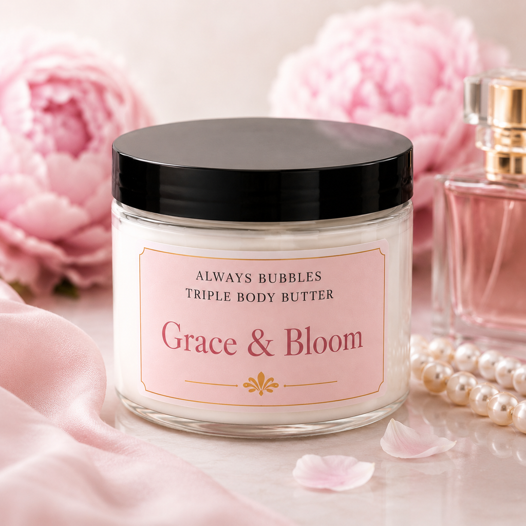 Always Bubbles Grace &amp; Bloom Triple Body Butter in a clear jar with a black lid, surrounded by soft pink peonies, pearls, and a perfume bottle.