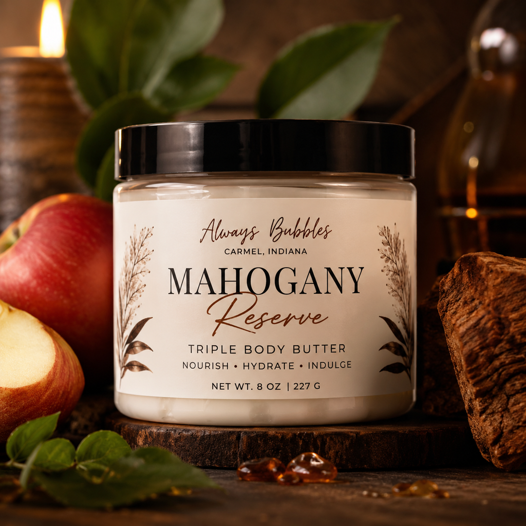 Always Bubbles Mahogany Reserve Triple Body Butter in a clear jar with a black lid, styled with crisp apples, rich mahogany wood, and warm amber accents.