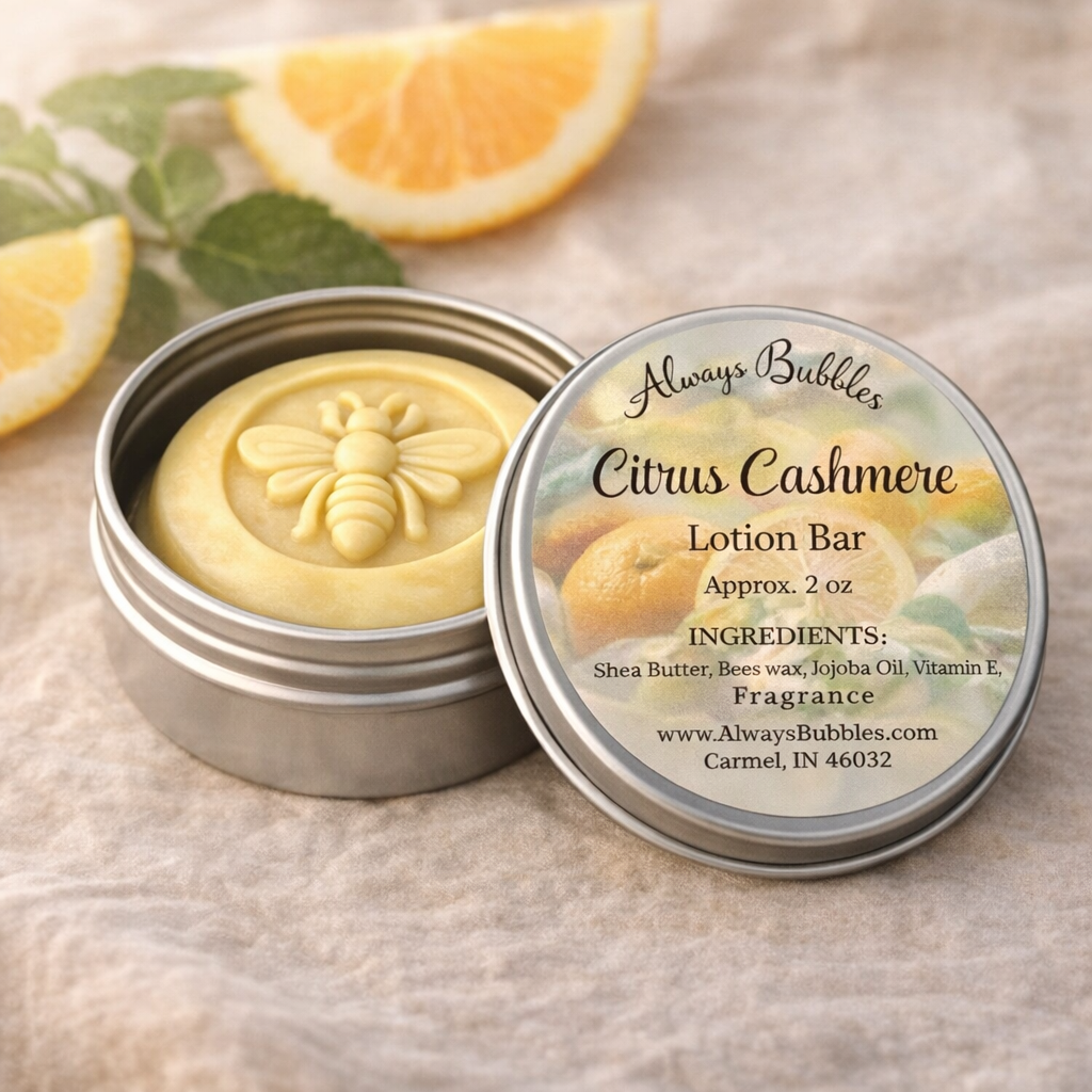 Always Bubbles Citrus Cashmere shea butter lotion bar with bee design in silver tin on soft linen with fresh citrus slices