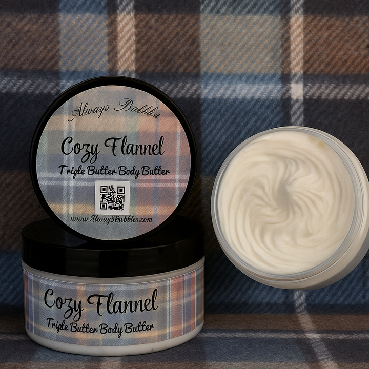 Always Bubbles Cozy Flannel Triple Body Butter in 8 oz jars on a blue plaid flannel background, with one jar open to show the whipped creamy texture and Always Bubbles script at the bottom.