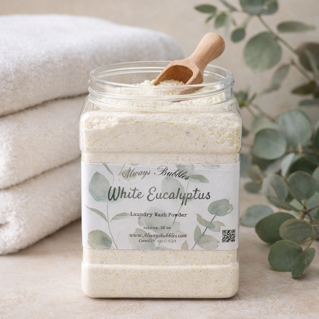Always Bubbles White Eucalyptus natural laundry wash powder in reusable container surrounded by fresh eucalyptus leaves and clean folded towels for eco-friendly fresh laundry.